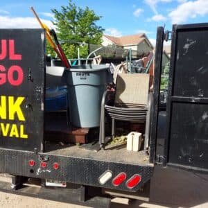 Trash truck filled with assorted junk, including a chair, bucket, and garden waste.