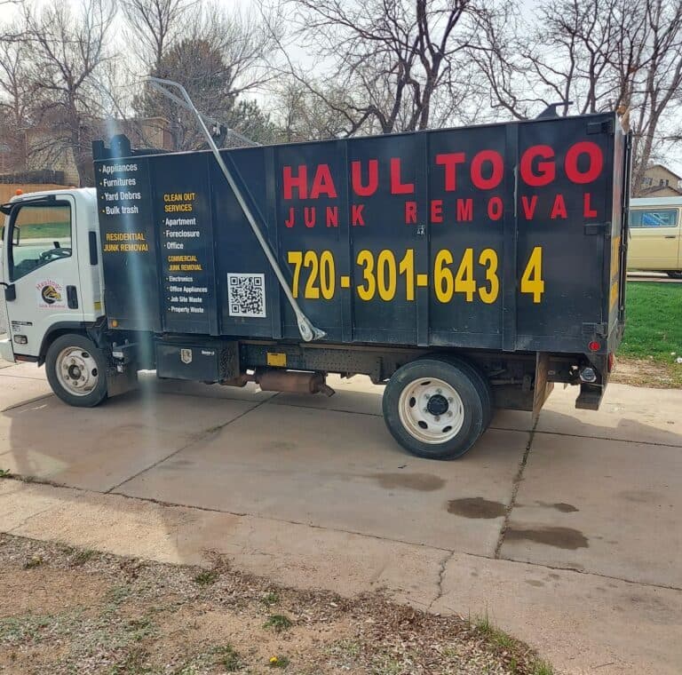 Junk removal truck parked with "Haul to Go" branding and contact information.